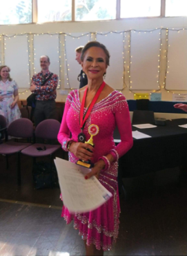 A person in a pink dress holding a trophy Description automatically generated
