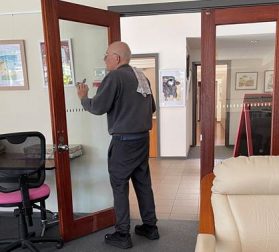 A man is holding a phone in front of a glass door, possibly taking a picture.
AI-generated content may be incorrect.