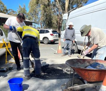 Several workers are busy working on a roadside construction site, with one man using a shovel and others in yellow vests.

AI-generated content may be incorrect.