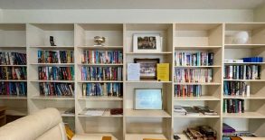 A bookshelf with many books and pictures

Description automatically generated